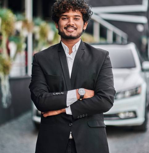 Indian businessman in the background of his white car.